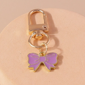 Vue détaillée du pendentif nœud en émail violet avec fermoir mousqueton doré pour sacs