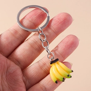 Creative realistic banana bunch keychain with silver metal ring on pink background