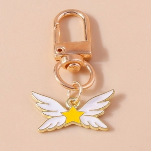 Détail d'un porte-clés doré avec pendentif aile blanche et étoile jaune en émail poli