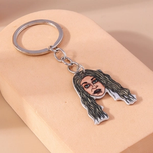 Close-up of a cartoon Halloween witch acrylic keychain on a pink display block