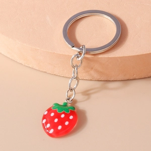 Close-up of a realistic strawberry keychain with a red resin fruit and green leaf detail