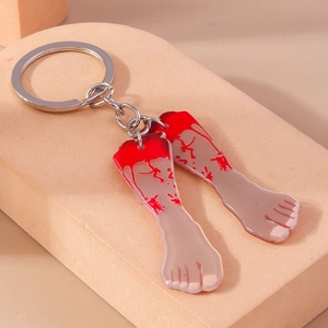 Close-up of bloody severed feet acrylic keychains with silver metal rings on pink base