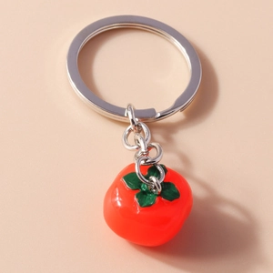 Detail of red persimmon keychain pendant with green leaves and silver metal ring