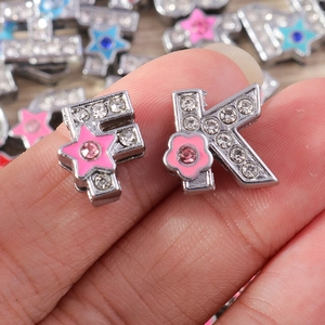 Detalle de dijes de letras con diamantes de imitación y detalles de estrellas y flores rosas