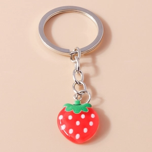 Macro shot of a cute red strawberry keychain with white polka dots and green leaf detail