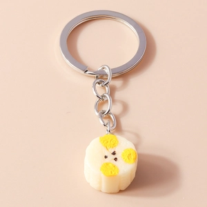 Close-up of a silver keychain featuring a cream-colored cartoon resin pendant with yellow details