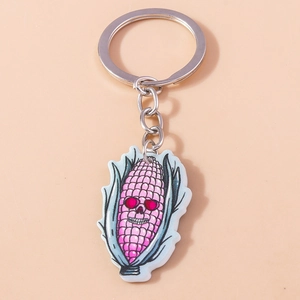 Detail shot of a corn skull keychain with pink kernels and green leaves on a pink background
