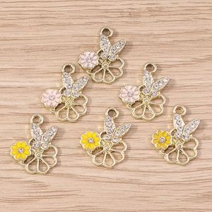 Détail de pendentifs papillon et fleur en alliage avec strass sur fond de bois