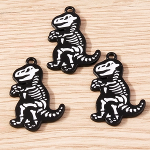 Close-up of black and white dinosaur skeleton alloy pendants on a light wood background