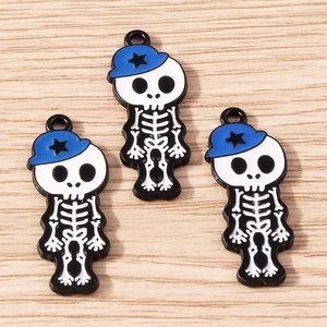 Detail view of 3 cartoon skeleton girl charms with blue hats on light wood background