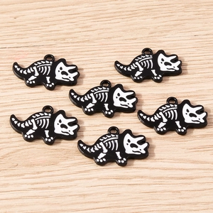 Set of 6 black and white dinosaur skull charms for DIY jewelry making on wood background
