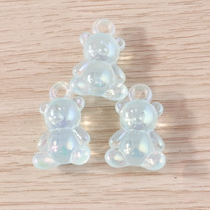 Three light blue translucent gummy bear pendants with iridescent AB coating on wood background