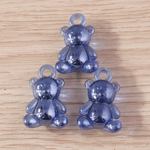 Three transparent dark blue resin gummy bear charms with loops on wood background
