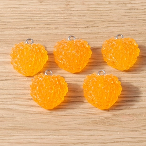 Détail de cinq breloques cœurs en résine orange à texture de baies et anneaux argentés DIY