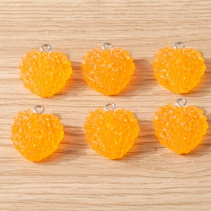 Vue macro de six pendentifs en forme de cœur orange avec surface texturée et anneaux en métal