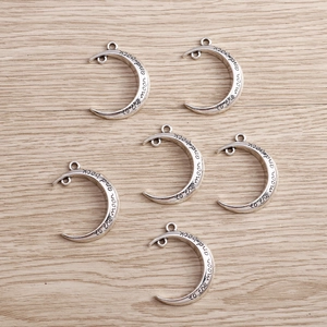 Detail of silver crescent moon charms engraved with to the moon and back text