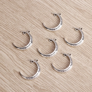 Detail of vintage silver moon pendants with To the moon and back engraved lettering