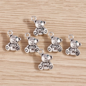 Macro detail of cute 3D teddy bear charms with bow ties and vintage silver finish