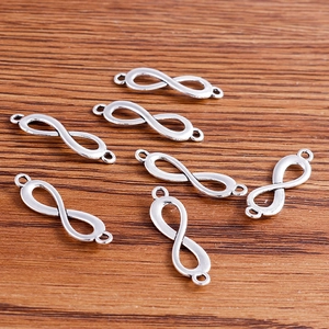 Silver infinity figure-eight jewelry connectors on a wooden background for DIY crafts