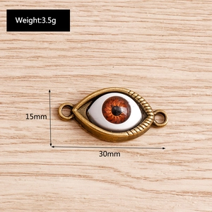Detailed view of bronze evil eye charms with dimensions 30mm by 15mm on wood surface