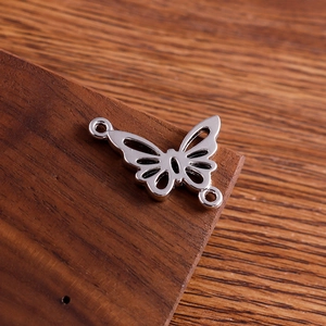 Close-up of silver hollow butterfly connectors for DIY jewelry making on wood