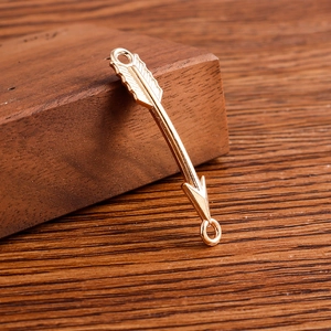 Vue macro de connecteurs de bijoux en forme de flèche dorée sur support en bois