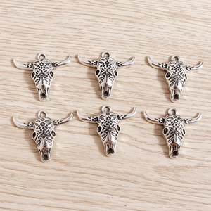 Detailed close-up of six vintage cow skull pendants with Bohemian patterns on wood background