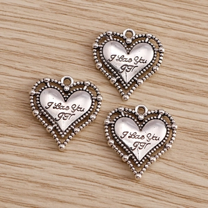 Vue détaillée de pendentifs en forme de cœur argent antique avec gravure I Love You sur bois