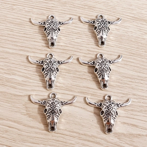 Close-up of six antique silver bull skull charms with boho patterns for DIY jewelry making