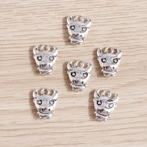 Flat lay of six silver ox head charms on a wood background for DIY jewelry making