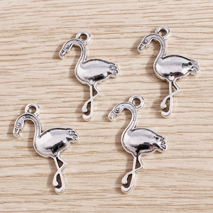 Detailed view of four silver flamingo charms with vintage texture on wood