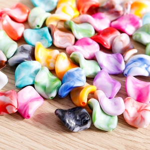 Close-up of colorful irregular marble-textured acrylic beads on a light wood background