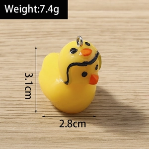 Détail d'un pendentif canard jaune en résine de 3,1 cm avec anneau sur fond de bois