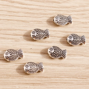 Macro shot of vintage silver fish-shaped beads for DIY jewelry and bracelets
