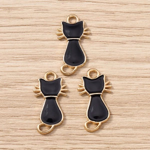 Vue détaillée des pendentifs chat en émail noir avec placage d'or sur fond bois