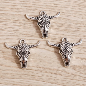 Detailed macro view of three vintage bull skull charms with ornate filigree on wood