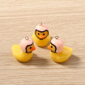 Détail de breloques canards jaunes avec casques roses pour fabrication de bijoux