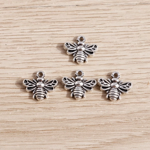 Detailed macro view of four vintage silver bee charms for jewelry making with hanging loops