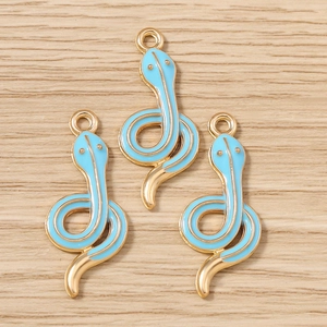 Macro detail of three light blue enamel snake charms with gold plating for jewelry making