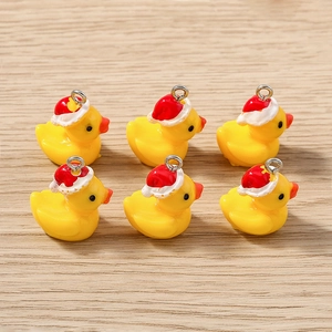 Détail de six pendentifs canards jaunes en résine avec bonnets de Noël rouges et anneaux