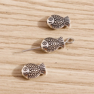 Detailed macro view of vintage silver fish-shaped beads with scales for DIY jewelry making