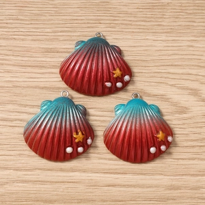 Detail of shell-shaped pendants with red-green gradient finish and pearl star accents