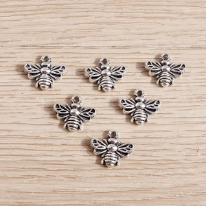 Detail view of six antique silver bee charms with hollow wings for DIY jewelry crafting