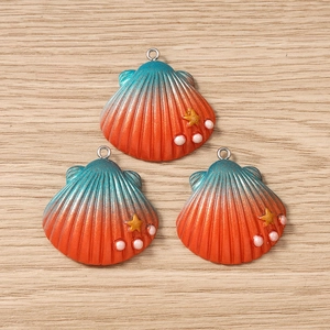 Macro detail of three gradient shell pendants with golden stars and white pearls on wood
