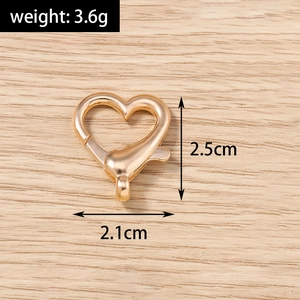 Macro di chiusura a moschettone dorata a cuore con dimensioni su sfondo legno chiaro