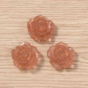 Macro dettagliata di tre ciondoli a rosa in resina rosa con scaglie di foglia d'oro