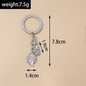 Detailed view of hedgehog and pineapple pendants on a silver metal keychain with dimensions