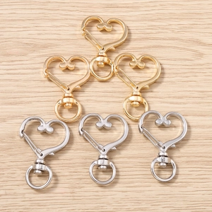 Dettaglio macro di ganci a molla a forma di cuore in oro e argento su legno