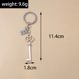 Detailed view of silver letter E keychain with rhinestones and vintage key pendant