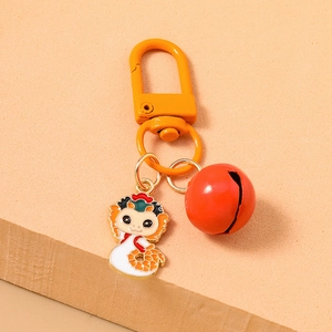 Cartoon zodiac dragon keychain with yellow carabiner and red bell on orange background